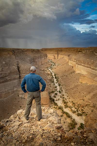 Man looking down at a Wadi in Yemen by Garth Fuchs